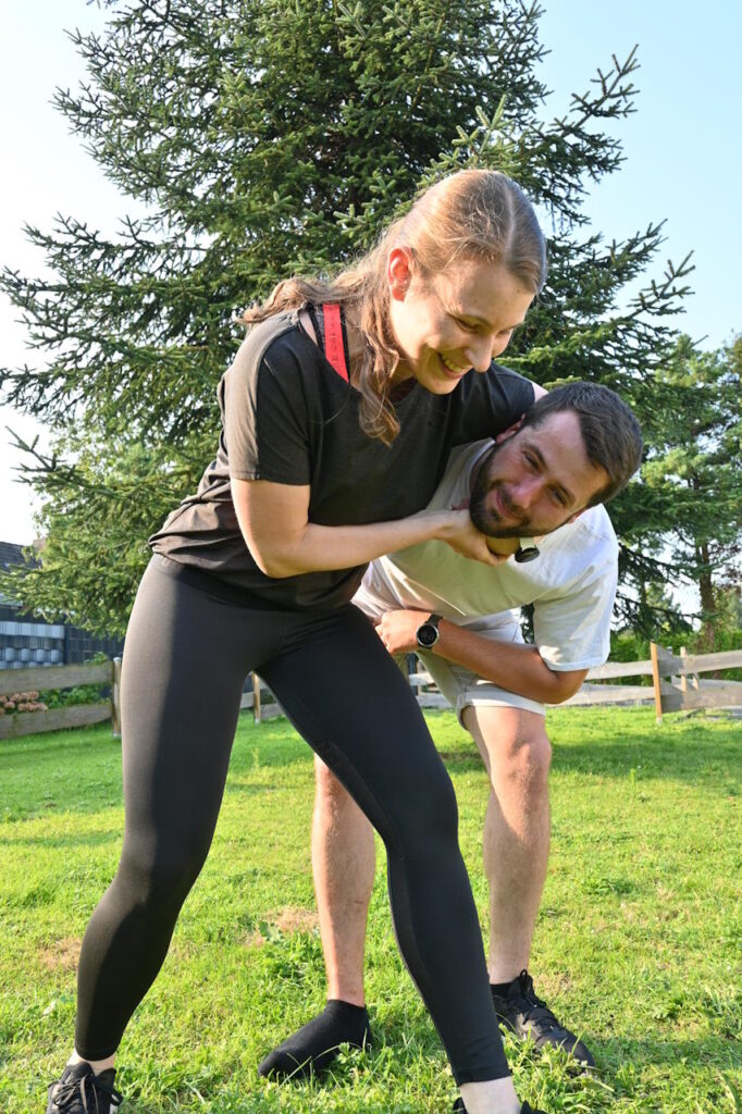 Coach Simone demonstriert eine Selbstverteidigungstechnik an einem Trainingspartner während eines Workshops im Freien.