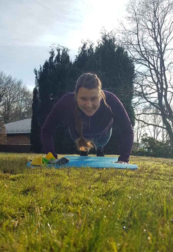 Simone beim Outdoor-Training, während sie eine Fitness Übung auf einer Matte durchführt.